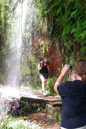 Walking under waterfall along levada path